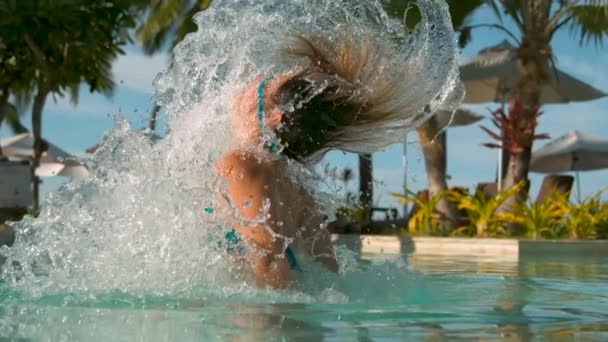 スローモーション クローズアップ 壮大な夏休みに喜びの若い女性は 彼女の髪と透明な水を飛び散らします 女性旅行者は プールから彼女の頭を鞭打ち 熱帯リゾートの周りに水をスプレー — ストック動画