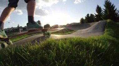 Yavaş Hareket, Düşük Açı, Lens Parlama: Tanınmaz genç adam beton pompa parça aşağı onun köpek arkadaşı iz tarafına bakar gibi longboarding. Kaykay üzerinde güzel bir akşam zevk Sporcu.