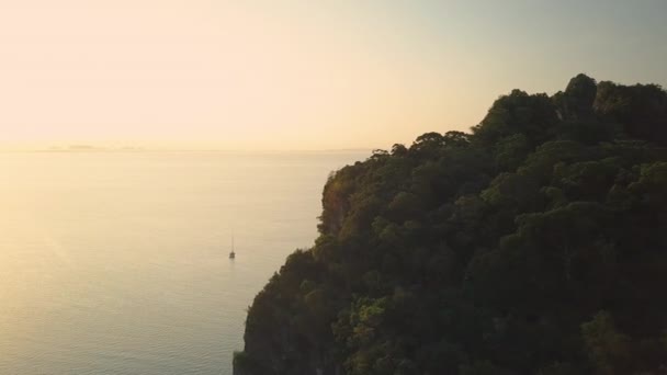 息をのむような黄金の夕日は タイの沿岸のボートや崖を照らす 静かなエメラルドの海と太陽が遠くに沈むのを航海する寂しいボートの牧歌的夏の夜の風景 — ストック動画