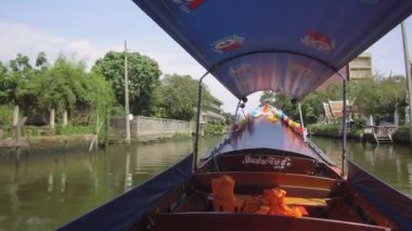 Düşük Açı: Ahşap Turist tekne taksi Chao Phraya nehir kıyısında yüksek harap binalar geçiyor. Güneşli bir yaz gününde kokulu Bangkok kanal ağı Sinematik longtail tekne gezi turu.