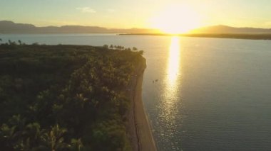 Anteni, Lens Flare: nefes kesen günbatımı güzel tropik ada ve tatil üzerinde parlayan doğru uçan. Sakin deniz uzak sahil tesisi Pasifik Adaları'nda yaklaşan muhteşem çekim