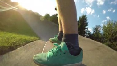 Düşük Açı, Close Up, Lens Flare: Tanınmaz patenci güneşli pompa parça aşağı longboard sürmek. Paten parkında güneşli bir akşam onun serin kaykay üzerinde engebeli beton iz boyunca Aktif erkek hızları.