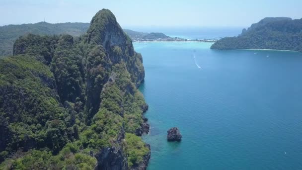 在泰国阳光明媚的旅游海滩附近 沿着巨大的石灰岩悬崖飞行 覆盖着郁郁葱葱的热带植物 巨大的岩溶地层在接近遥远海滩的蓝色海浪中翱翔 — 图库视频影像