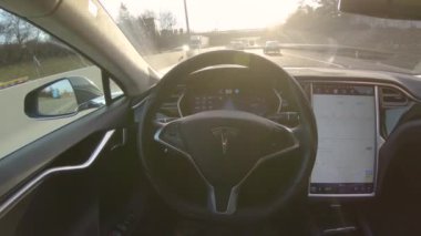 Özerk araba - 1 Şubat 2017: erkek sürücünün direksiyon oturan ve özerk kendi kendine sürüş otomatik pilot Tesla Model S Sürücüsüz araç dinlendirici ve rahat sürüş keyfi