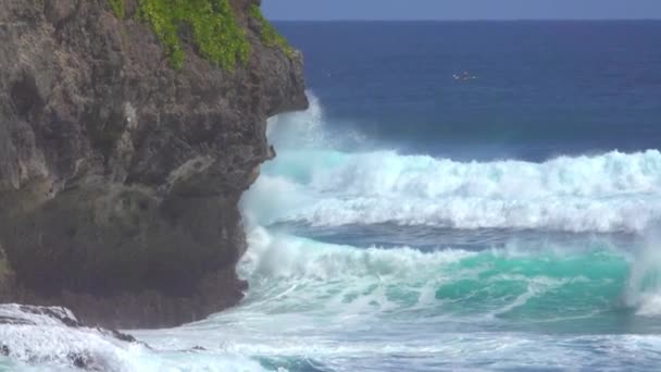 慢动作 惩罚翡翠色的海浪击中黑色悬崖在一个阳光明媚的一天 在偏远的热带岛屿 蓝色桶波的风景如画的镜头滚动到巴厘岛雄伟的岩石悬崖 — 图库视频影像