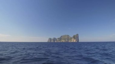 Hava: güneşli turist beach Tayland yakınındaki gür tropikal yeşil kaplı büyük kalker uçurum boyunca uçan. Büyük karstik oluşumu uzak beach yaklaşan mavi okyanus dalgaları üzerinde yükselir.