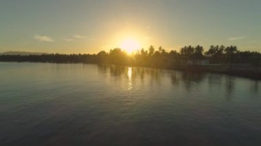 Anteni, Lens Flare: nefes kesen günbatımı güzel tropik ada ve tatil üzerinde parlayan doğru uçan. Sakin deniz uzak sahil tesisi Pasifik Adaları'nda yaklaşan muhteşem çekim