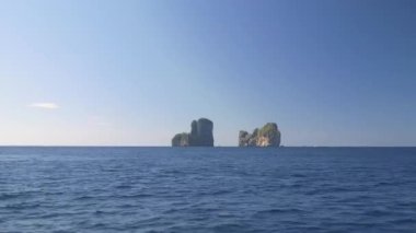 Hava: güneşli turist beach Tayland yakınındaki gür tropikal yeşil kaplı büyük kalker uçurum boyunca uçan. Büyük karstik oluşumu uzak beach yaklaşan mavi okyanus dalgaları üzerinde yükselir.