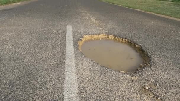 Low Angle Close Large Gaping Pothole Filled Muddy Water Sticks — Stock Video