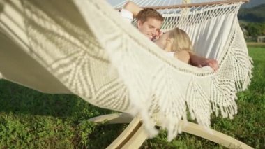 Slow Motion: Lovestruck kız arkadaşı ve erkek arkadaşı doğada romantik hamakta konuşuyor. Onlar güneşli bahar kırsal da askı dinlenmek gibi güzel çift konuşuyor. Mutlu erkek ve kız salıncakta konuşuyor