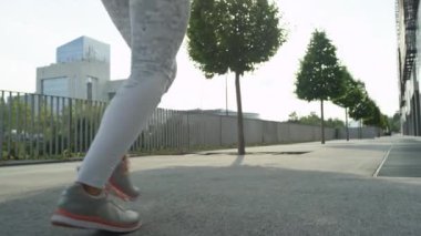 Slow Motion Close Up: Tanınmayan genç kadın güneşli sabah şehir sokaklarında çalışmadan önce koşu. Atletik kız zihnini temizlemek için blok etrafında çalışan. Kentsel ortamda egzersiz