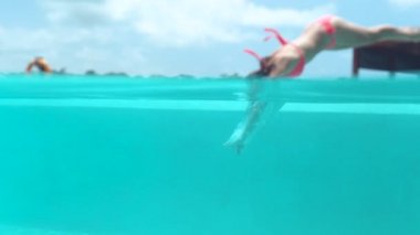 Su, palmiye ağacı ormanda Cennet Adası güneşli Bali tatil yaz zevk sıçramasına ağır çekim yakın kadar güzel gülümseyen kız pembe bikini mayo sonsuzluk havuzu, kenarında oturan