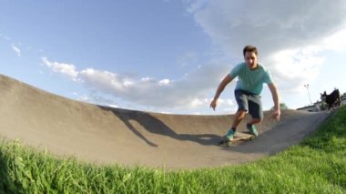 Yavaş Hareket Yakın Çekim Düşük Açı: Neşeli kaykaycı o sevimli arkadaşı köpek ile hızları gibi kamera shaka işareti verir. Stoked longboarder paten parkında sinematik sabah köpek tarafından takip ediliyor