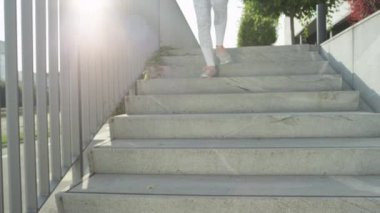 Yavaş Hareket, Düşük Açı, Lens Parlaması: Beyaz bilinmeyen uygun kız sabah beton merdivenlerden aşağı çalışır. Sıkıştırma giyim genç kadın şehir sokaklarında çalışma, merdivenlerden aşağı koşu.