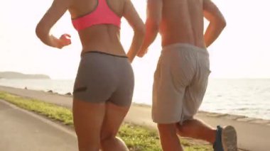 Genç erkek arkadaşı ve kız arkadaşı birlikte güneşli sahilde jogging. Huzurlu okyanus boyunca sportif Tarih jog üzerinde kadın aktif adam. Yaz aylarında açık havada egzersiz mutlu çift.