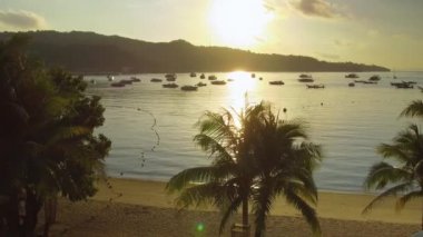 Hava Lens Flare: Phi Phi Islands çarpıcı sakin bay pitoresk tropikal günbatımı aydınlatır. Güzel altın güneş ışınları sakin kum plajındaki Parlatıcı ve tekneler demirli. Nefes kesen yaz gecesi