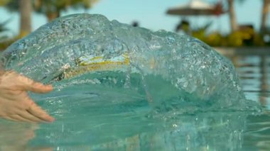 Slow Motion, Close Up: Destansı cennet adası havuzunda duran genç kadın suyla oynuyor. Serinletici havuzda uzanan oyuncu kadın gezgin, avucuyla serin bir dalga yapıyor. Kız kepçe havuz suyu