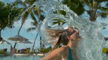 Slow Motion, Close Up, Reversed: Kız havuzdan başını çeker ve okyanus kıyısındaki tatil beldesinde güneşli bir günde saçlarını geri çevirir. Güzel havuzda saçları ile oynayan mutlu kadın Awesome çekim.