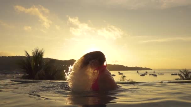 慢动作 镜头火焰 快乐的女人翻转她的长发 在海滨无边泳池放松的夜晚浸 年轻女孩玩她的头发在空池与风景如画的景色 — 图库视频影像
