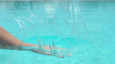 Slow Motion, Close Up: Tanınmayan kadının eli, Pasifik Adaları'ndaki cennet beldesinde güneşli yaz gününde sakin havuz suyuna zorla vurur. Serinletici su tokat kız Sinematik atış.