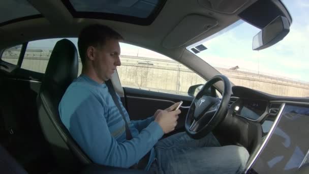 テスラの自動運転車 3月2018 無責任なドライバーは 激しいラッシュアワーのトラフィックを運転しながら 彼のスマートフォンをチェックします 彼の自律走行車が忙しい高速道路に沿って自分自身を駆動しながら 男性のテキストメッセージ — ストック動画