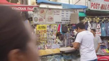 Bangkok, Tayland - Mart 2017, Close Up: Taylandlı erkek, kalabalık giyim tezgahlarının yakınında yerel lezzetler hazırlarken Khao San yolunun etrafına bakıyor. Genç Asyalı adam çeşitli lezzetli Tay yemekleri pişirme. 