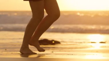 Yavaş Hareket, Lens Flare: Yaz akşamı altın ışıklı plajda çalışan bilinmeyen kadın. Muhteşem gün batımında kumlu plajda koşan koşucu. Bilinmeyen sporcu üzerinde parlayan güzel altın renkli gece.