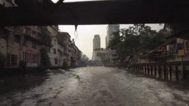 Bangkok, Tayland - Mart 2017 Lens Flare: Güneşli bir akşamda Chao Phraya nehrinin kirli kanallarında sürükleniyor. Şehir alanını geçerken su taksisinin neden olduğu dalgalanan kanal suyunun sinematik çekimi