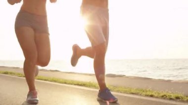 Close Up, Lens Flare: Gülümseyen Kafkas çift güneşli okyanus yolu boyunca çalışır. Genç erkek arkadaşı ve kız arkadaşı deniz kenarında yaz tatili sırasında rahatlatıcı çalıştırmak. Sportif tarihte kadın ve erkek.