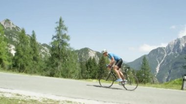 Yol bisikletçi dalgalar ve kolayca yenilikçi elektrikli bisiklet gurl tarafından overtaken Yorumlar mücadele. Sundress pedallar pro dağ bisikleti rider güneşli yaz aylarında geçmiş kadında sarışın şehir.
