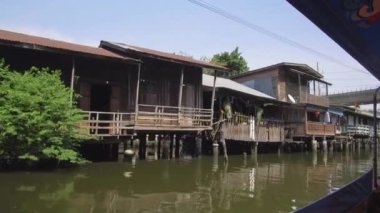 Tayland kirlenmiş nehrin yanında duran Düşük Açılı Kasvetli ahşap evler. Bangkok'un fakir bölgesini geçen kirli ve kokulu Chao Phraya nehri, gezi turları için turistik bir cazibe merkezi olarak hizmet vermektedir.