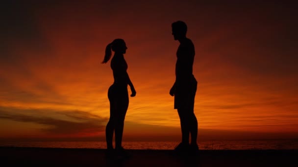 Медленное движение, низкий угол обзора: счастливый молодой человек и женщина дают пять на потрясающем закате . — стоковое видео