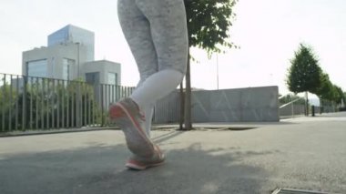 Slow Motion Close Up: Tanınmayan genç kadın güneşli sabah şehir sokaklarında çalışmadan önce koşu. Atletik kız zihnini temizlemek için blok etrafında çalışan. Kentsel ortamda egzersiz