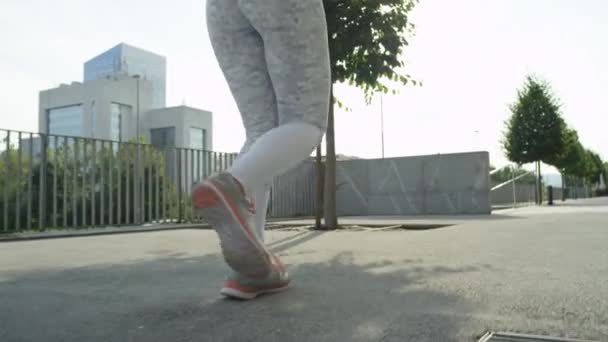 スローモーションクローズアップ 晴れた朝に街の通りで仕事の前にジョギングを認識できない若い女性 彼女の心をクリアするためにブロックの周りを走り回る運動の女の子 都市環境での運動 — ストック動画