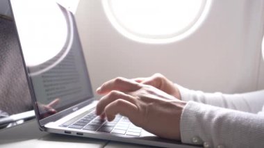 Yakın: Şık gümüş ve siyah Dizüstü Klavye uzun bir uçuş beyaz kadın'ın parmak tipi. Tanınmayan kadın girişimci acil iş toplantısı için uçar iken onun notları yazma