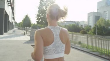 Yavaş Hareket Yakın Çekim Lens flare: güzel bir güneşli günde şehir sokaklarında koşu tanınmayan sarışın kız. Kentsel bir ortamda çalışan bir kadın. Zihninizi temizlemek için sıcak bir günde koşmak.