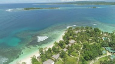 AERIAL: Flying over peaceful paradise island hotel resort on perfect summer day. Spectacular shot of empty white sand beaches and emerald ocean water meeting on sunny afternoon on tropical islands.