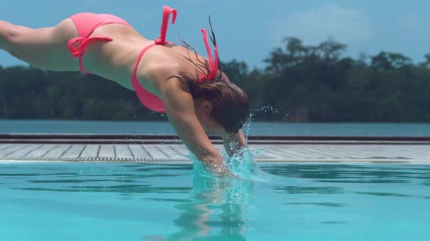 スローモーション クローズアップ 幸せな女性観光客はバヌアツの暑い熱帯の夏の間に穏やかなプールに最初にジャンプします 若い女性は彼女の素晴らしい休日にくつろぎ さわやかなターコイズブルーの水に飛び込みます — ストック動画