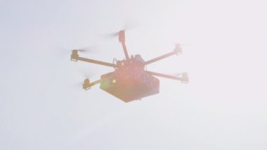 Closeup Lens Flare İhA drone mal teslim. Kargo multicopter ile son dakika hediye teslimatı. Evinize doğum günü hediyesi getiren drone'u gönderiyor. Fütüristik drone güneş üzerinde Noel hediyesi uçan
