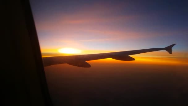 看着窗外 同时在密云上空飞行到浪漫的金色光日落 人们在日出时乘坐喷气式客机旅行 飞机机翼的细节 — 图库视频影像