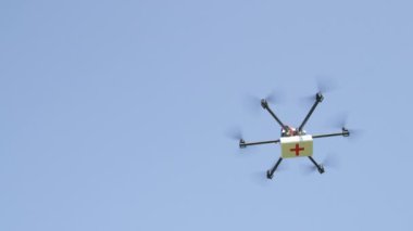Close Up: İhA Drone teslimatı. Multicopter yükselen ve ilk yardım paketi ile uçan. Sos ilaçlarını teslim eden drone. İlk müdahale uçağıyla tıbbi hava sevkiyatı. İhA ile hava lojistik ve ulaşım