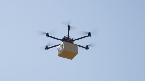 Bouclez la livraison de drones UAV. Multicopter volant grand paquet brun sur ciel bleu. Drone livraison paquet postal à votre domicile. Expédition futuriste par drone d'hélicoptère. Logistique et transport multirotors 