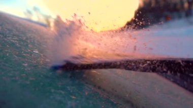 Slow Motion Close Up Dof: Altın gün doğumunda bir araba penceresinden sabah dontemizliği kişi. Donmuş bir arabanın ön camından ses kısıklığı, güneşin üzerinde akan kar taneleri. Kazıyıcı don kaldırma