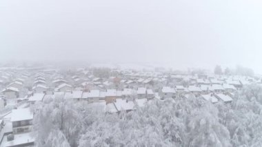 Hava: Kış gününde taze karla kaplı çatıları ile sessiz banliyö kasabası üzerinde uçan. Karlı kış gününde pastoral sıra evler. Huzurlu banliyösünde banliyö çatıları ve karlı arka bahçeleri üzerinde Uçan.