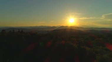 Hava: Altın batan güneşe doğru çarpıcı orman ağaç tepelerinde uçan. Yemyeşil ormanın üzerinde muhteşem gün doğumu. Işıklı ormanın üzerinde uçmak, gün batımında uçsuz bucaksız tepeleri ve vadileri ortaya çıkarmak