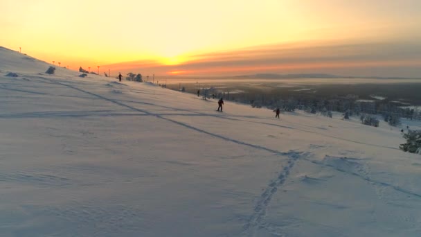 空中组无法辨认的滑雪者滑雪下雪山 在冬季日落 在芬兰利维的金色日出中 人们在滑雪时滑雪新鲜的粉雪 阳光明媚的冬季早晨的冬季活动 — 图库视频影像