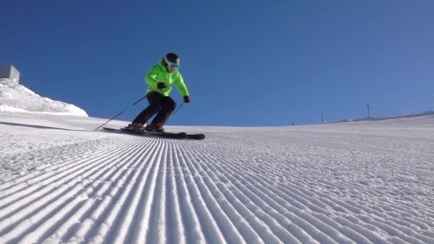 スローモーション 趣味のためにスキーをし 他の人と雲のない日に晴れた冬のアルプスの近代的なヨーロッパのスキーリゾートで雪の新鮮な手入れピストをオンに彫刻を行う — ストック動画