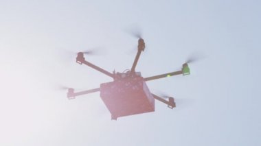 Closeup Lens Flare İhA drone mal teslim. Kargo multicopter ile son dakika hediye teslimatı. Evinize doğum günü hediyesi getiren drone'u gönderiyor. Fütüristik drone güneş üzerinde Noel hediyesi uçan