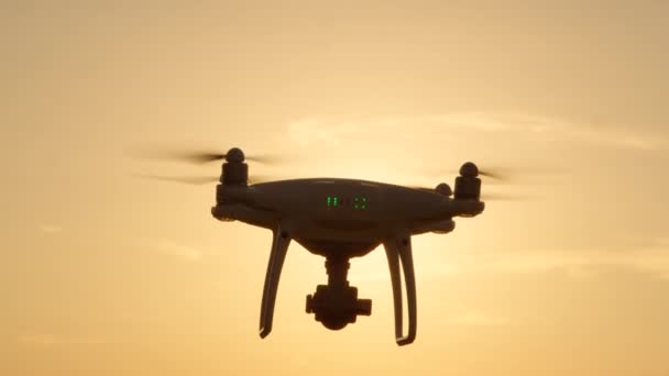 小型拍摄无人机飞过金色的日落天空 白色四轴飞行器无人机 在金光下与附加相机拍摄 四轴直升机飞越日出天空 — 图库视频影像