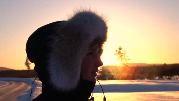 慢动作特写 在寒冷的冬日 在金色的夕阳下 从年轻女子的嘴里呼吸出蒸汽 头戴头罩的女孩在早晨的日出中呼吸着蒸汽 冬天的人 — 图库视频影像